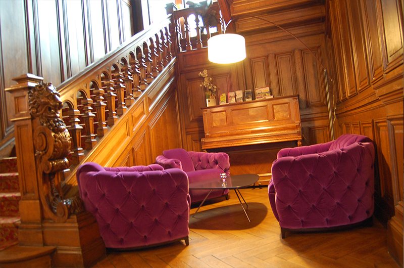 Le salon au pied de l'escalier de bois sculpté, fauteuils de velours
