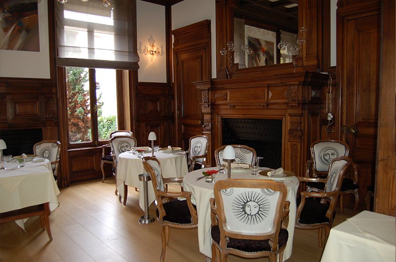 Salle à manger lambrissée, cheminée et tables rondes nappées