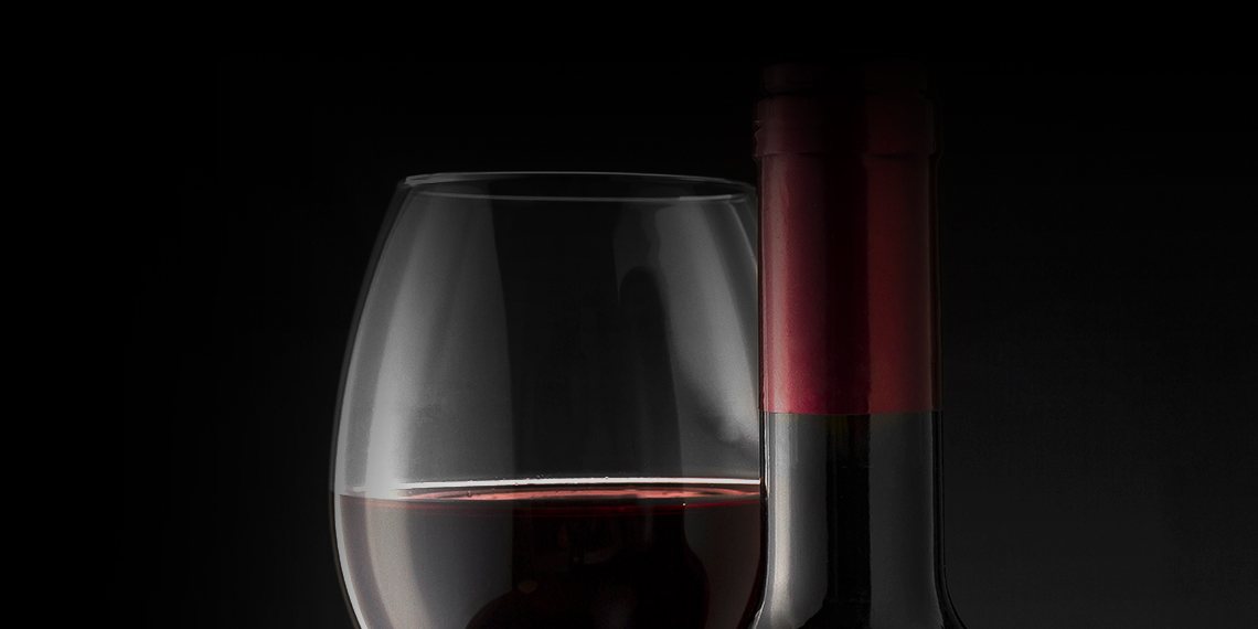 Un verre de vin rouge et une bouteille sur fond noir